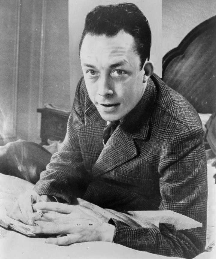 Albert_Camus,_gagnant_de_prix_Nobel,_portrait_en_buste,_posé_au_bureau,_faisant_face_à_gauche,_cigarette_de_tabagisme